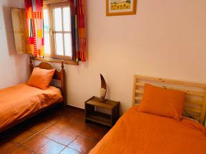 a bedroom with two beds and a window and a table at coqueto apto EILA 100 metros playa WIFI in Famara