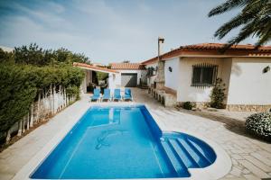 a swimming pool with two chairs and a house at Llastres in Miami Platja