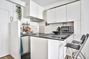 a white kitchen with white cabinets and a chair at Nice apartment at 10 min from Bastille in Paris