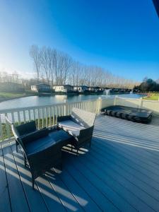 a deck with two chairs and a bench on the water at Bridgewater Lodge with Hot Tub in York