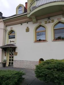 ein weißes Gebäude mit Fenstern und einem Schild darauf in der Unterkunft Bianco in Sopron