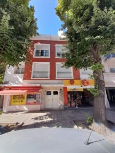 un edificio rojo con un árbol delante de él en Departamento 4 personas Colon 2900 en Mar del Plata