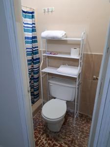 a bathroom with a toilet and towels on shelves at Hostal Lima Verde in La Lima