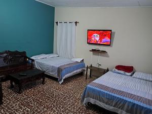 a bedroom with two beds and a tv on the wall at Hostal Lima Verde in La Lima
