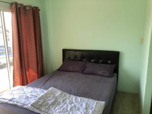 a bedroom with a bed with purple sheets and a window at บ้านยายกิ้ว in Phra Nakhon Si Ayutthaya