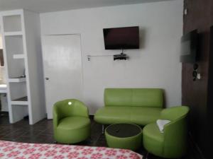 a living room with green chairs and a tv at Cozy apartment in an Ecotourism El Tascate Rancho in Cuauhtémoc