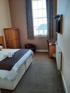 a hotel room with a bed and a window at Grammar Lodge Guest House in Campbeltown