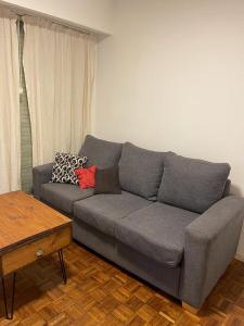 a gray couch in a living room with a table at Obelisco in Buenos Aires