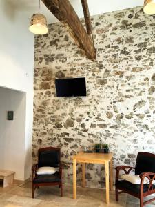 Habitación con 2 sillas, mesa y TV en una pared de piedra. en "La Petite Félixière" en Saint-André-de-la-Marche