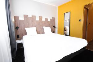a bedroom with a large bed and a yellow wall at Hôtel Les 2 Alpes L'Orée Des Pistes in Les Deux Alpes