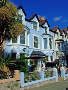 a large white house with people sitting outside of it at The Rosedene in Llandudno