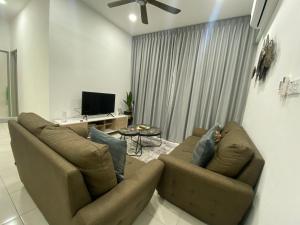 a living room with two brown couches and a tv at The Vista Apartment @ Demak Laut in Kuching