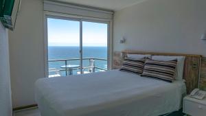 a bedroom with a bed with a view of the ocean at Dei Templi Apart Hotel in Viña del Mar