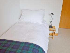 a large white bed with a pillow and a table at West Bothy in Glenborrodale