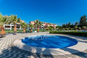 een zwembad op een patio met palmbomen en huizen bij El Rincón del Golf III by Ĥ in Isla Canela