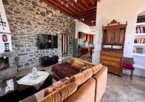 - un salon avec un canapé et un mur en pierre dans l'établissement Πέτρινο Εξοχικό Σπίτι στη Σύρο, à Firókambos