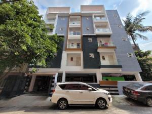 a white car parked in front of a building at StayhomeStays Prime in Bangalore