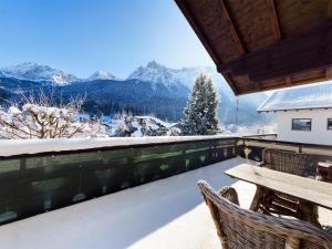 uma varanda com uma mesa e cadeiras e montanhas cobertas de neve em Schnitzerstube em Mittenwald