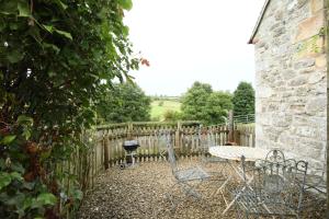 a patio with a table and chairs next to a fence at Dumble Cottage in Ashbourne