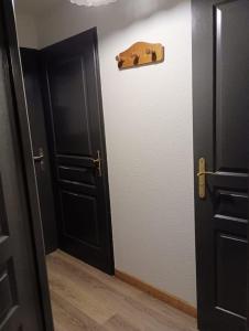 - un couloir avec une porte noire et du parquet dans l'établissement Appart. lumineux à St-Sorlin d'Arves (Sybelles), à Saint-Sorlin-dʼArves