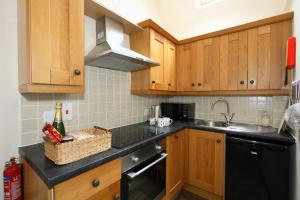 a kitchen with wooden cabinets and a sink at Dumble Cottage in Ashbourne