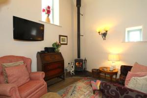 a living room with a couch and a tv on the wall at Dumble Cottage in Ashbourne