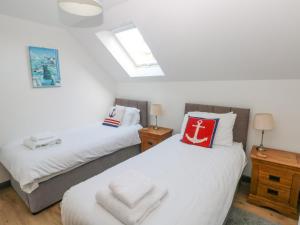 duas camas num quarto com dois candeeiros e uma janela em The Boathouse em Tenby