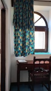 Pokój z biurkiem i oknem z zasłoną w obiekcie Warere Town House by Zanzibar Gem w mieście Zanzibar