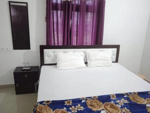 a bedroom with a white bed with a purple curtain at HOTEL SAMRAT PALACE in Ayodhya