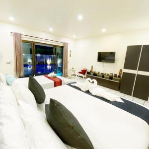 a hotel room with four beds and a flat screen tv at Wan Wan พูลวิลล่า พัทยา in Nong Prue