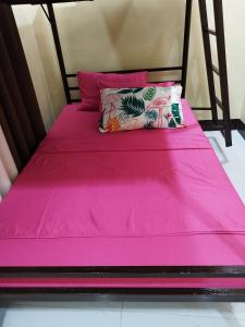 - un lit avec des draps roses et un oreiller dans l'établissement 30pax-Jumongs Transient Inn, à Bantay