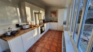 a kitchen with white cabinets and a tile floor at Holly Cottage, Hidden gem in the Yorkshire wolds in Welton