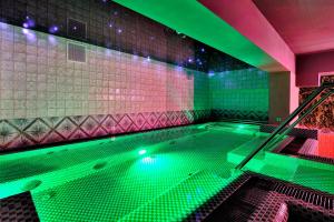 a large swimming pool with green lights in a room at Domki Mazurskie w Ogrodach Złotej Łani Wiartel - Klimatyczne Apartamenty i Pokoje Widokowe in Wiartel