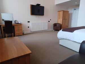a hotel room with a bed and a desk and a television at Grammar Lodge Guest House in Campbeltown