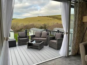 a porch with wicker chairs and a table on a deck at Mawgan Pads Lazy Days Lodge in Mawgan Porth