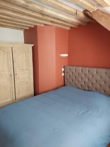 a bedroom with a blue bed and orange walls at Un Brin de folie dans le centre de Honfleur in Honfleur