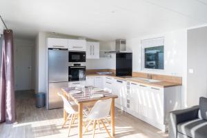 a kitchen with white cabinets and a table with chairs at Chalet neuf pour 6 dans une résidence avec piscine in Brétignolles-sur-Mer