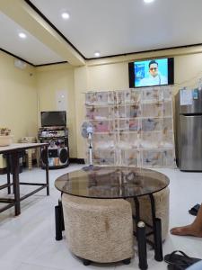 Habitación con mesa y TV en la pared. en 30pax-Jumongs Transient Inn, en Bantay