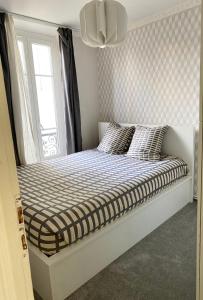 a bed in a room with a window at Cosy T2 in Neuilly sur Seine metro 1 in Neuilly-sur-Seine