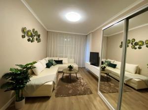 a living room with a couch and a tv at Liget Hévíz Apartman in Hévíz