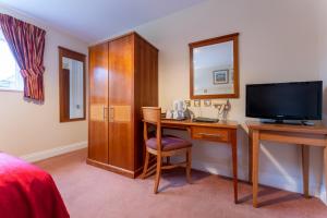 a hotel room with a desk and a television at The Evenhill in Canterbury