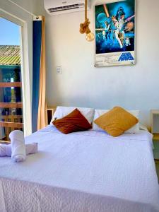 a bedroom with a white bed with two pillows on it at Pousada Hostel Albergue Explorer in Praia do Rosa