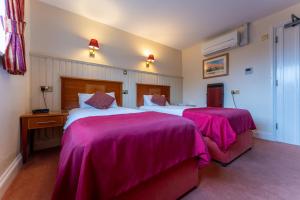 a bedroom with two beds with pink blankets at The Evenhill in Canterbury