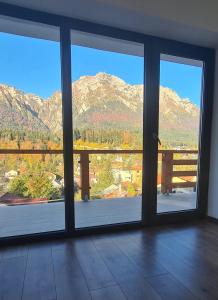 a room with a large window with views of mountains at ZEFIR APARTMENTS in Buşteni