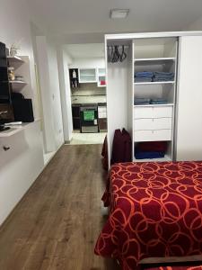 1 dormitorio con cama roja y cocina en MIKA APART TEMPORARIO ITALIANO en Buenos Aires