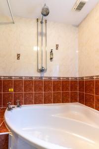 y baño con bañera y azulejos marrones. en The Evenhill en Canterbury