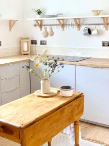 uma cozinha com uma mesa de madeira com flores em Woodview Cottage em Glamis