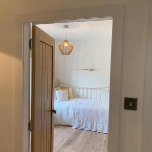 a bedroom with a white bed and a pendant light at Woodview Cottage in Glamis