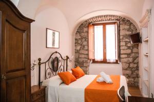 a bedroom with a bed with orange pillows and a window at S’ammentu house in Bosa