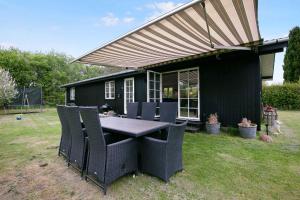 a table and chairs in front of a black house at Nyistandsat sommerhus med kærlighed og sjæl in Kyndeløse